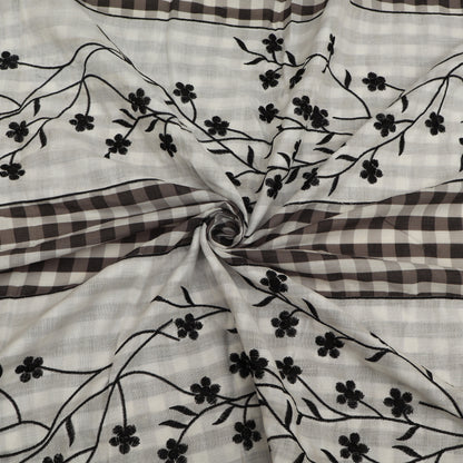 Fabric with black floral embroidery on a checkered pattern
