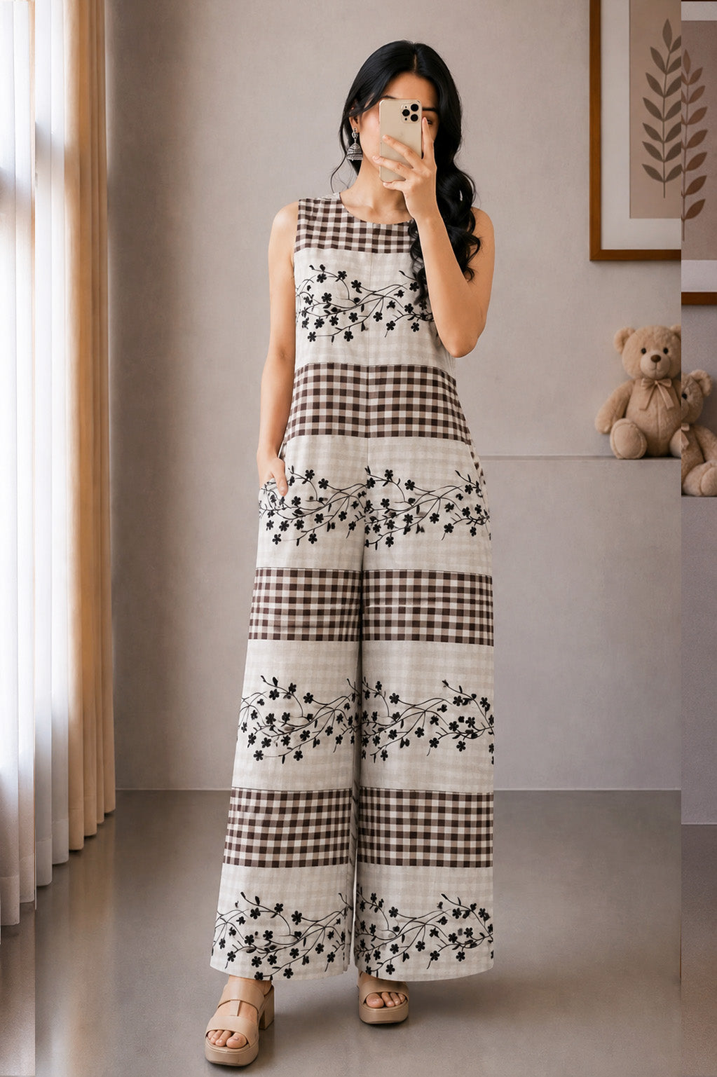 Woman taking a mirror selfie wearing a black and white checkered dress with floral patterns.