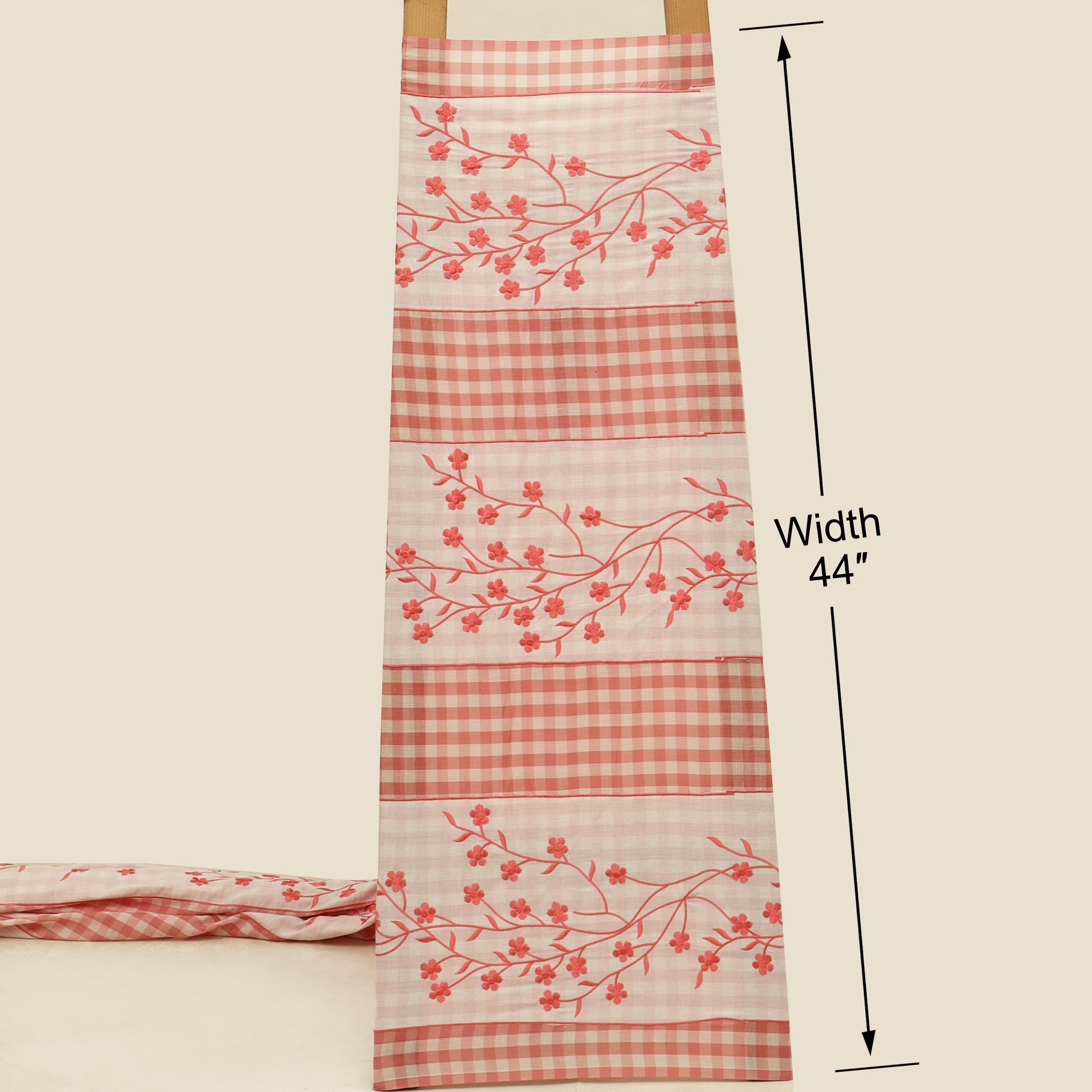 Fabric with red checkered and floral patterns on a beige background, showing width measurement.