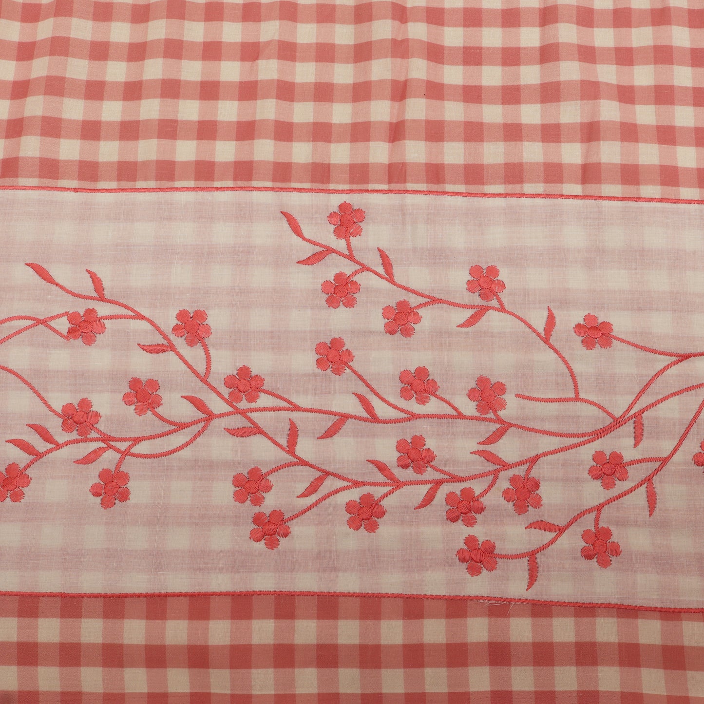 Red floral embroidery on a red and white checkered fabric background