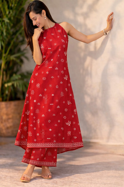 Woman wearing a red traditional outfit with white patterns against a neutral background
