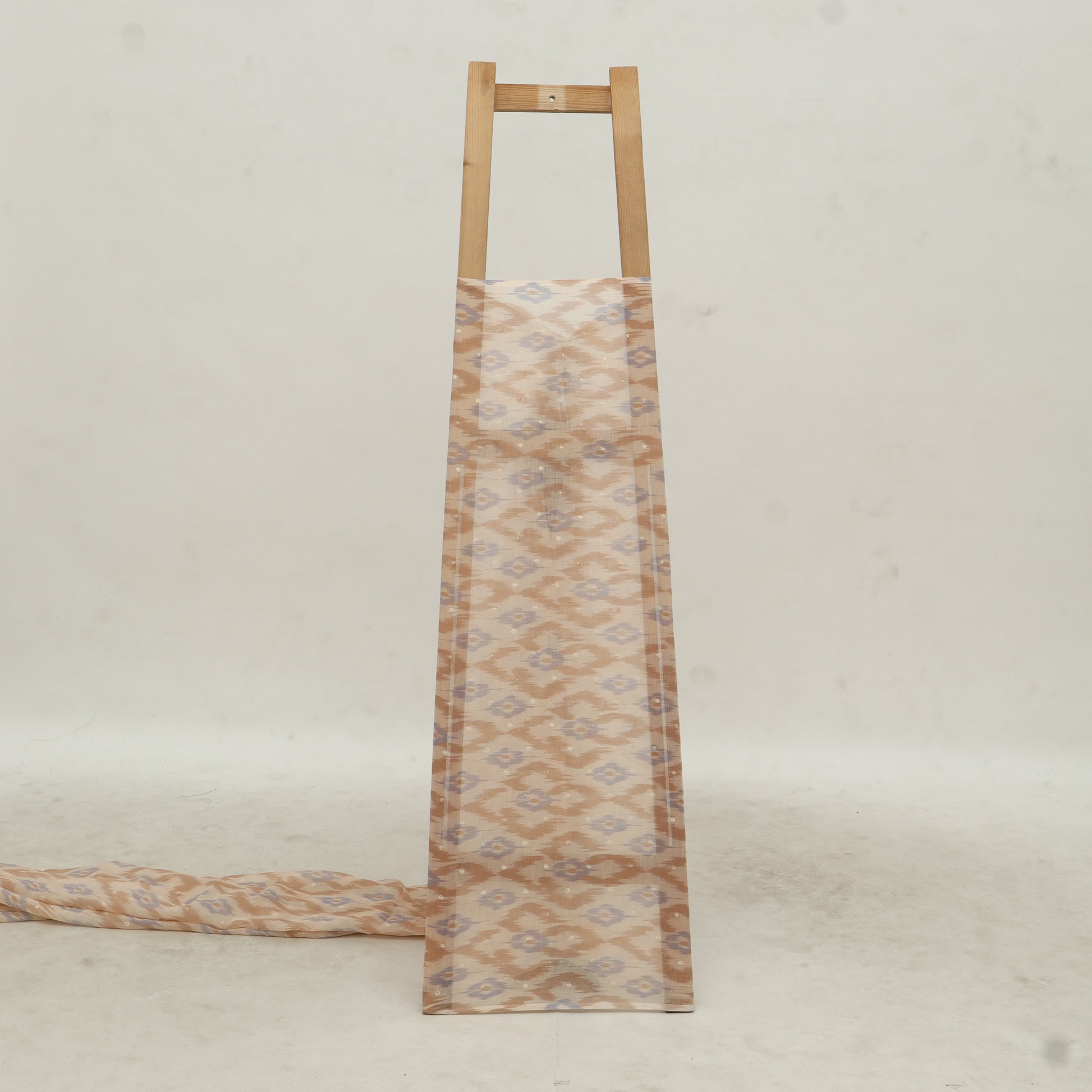 Fabric strip with a geometric pattern hanging on a wooden rod against a light background