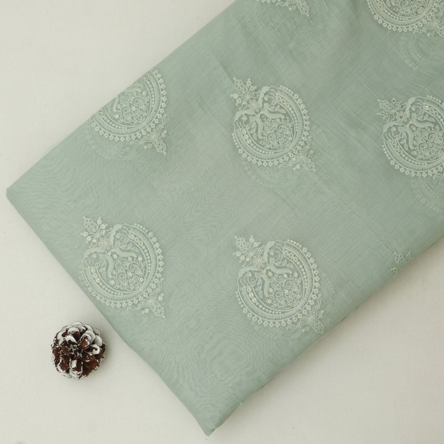 Light green fabric with decorative patterns on a white background
