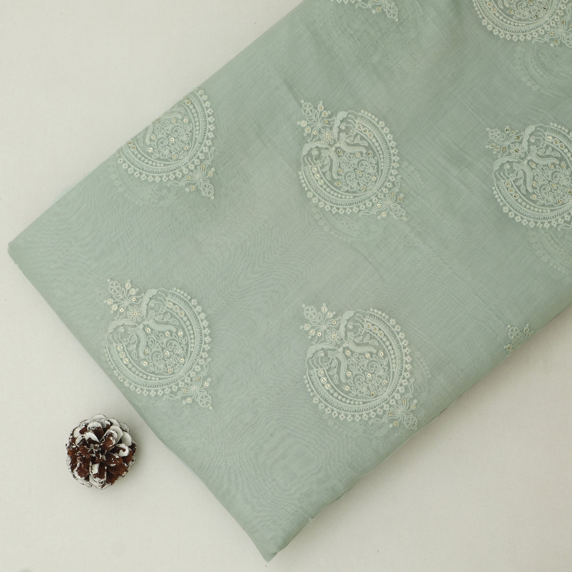 Light green fabric with decorative patterns on a white background
