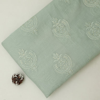 Light green fabric with decorative patterns on a white background
