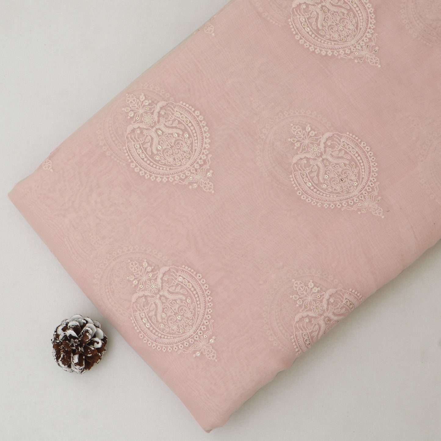 Pink fabric with white floral patterns on a light gray background