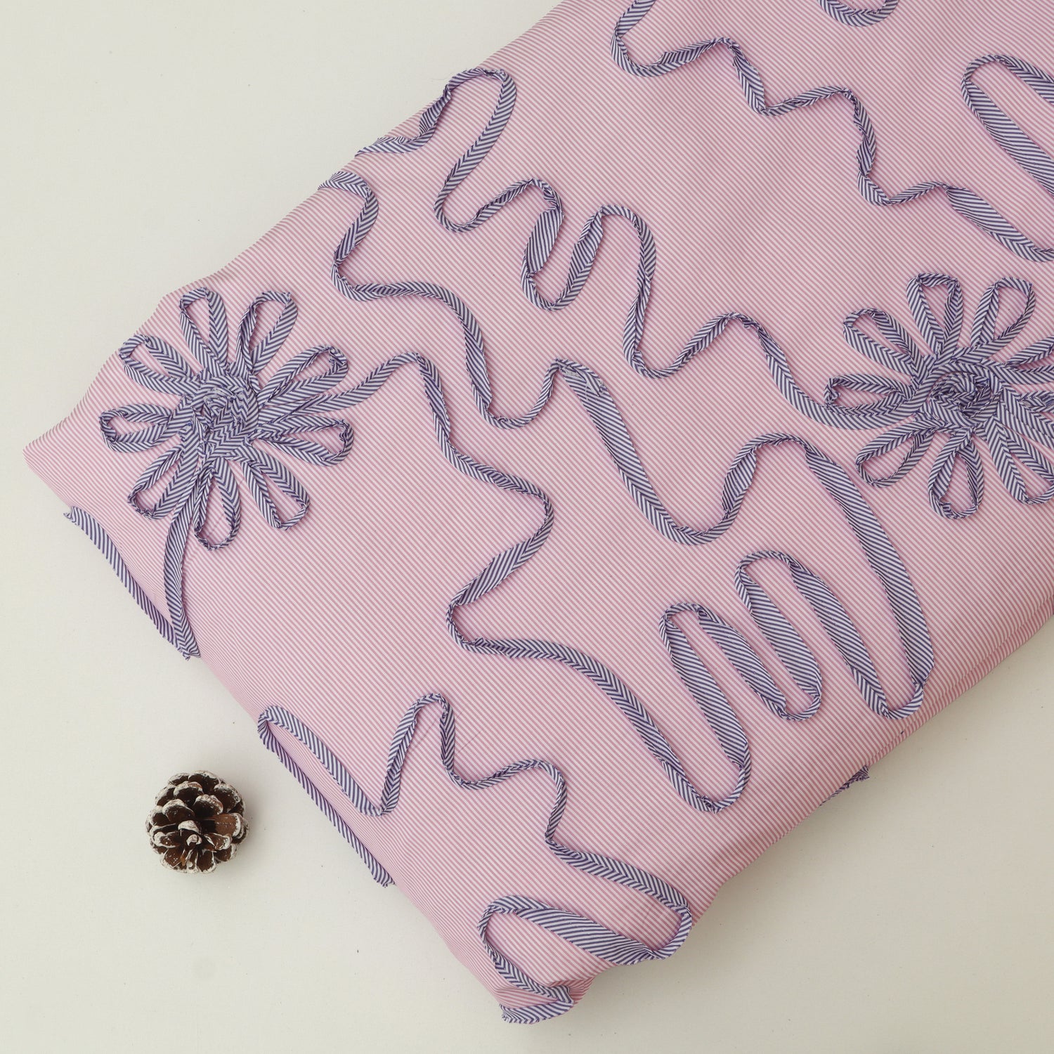 Pink fabric with embroidered designs on a light background