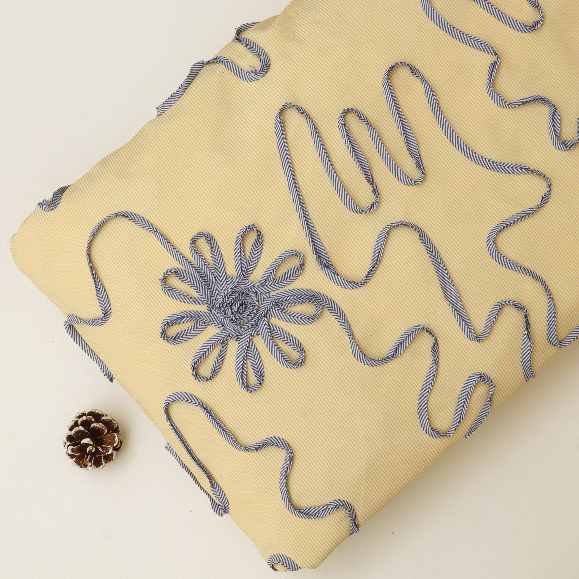 Beige pillow with blue embroidered floral design on a light background