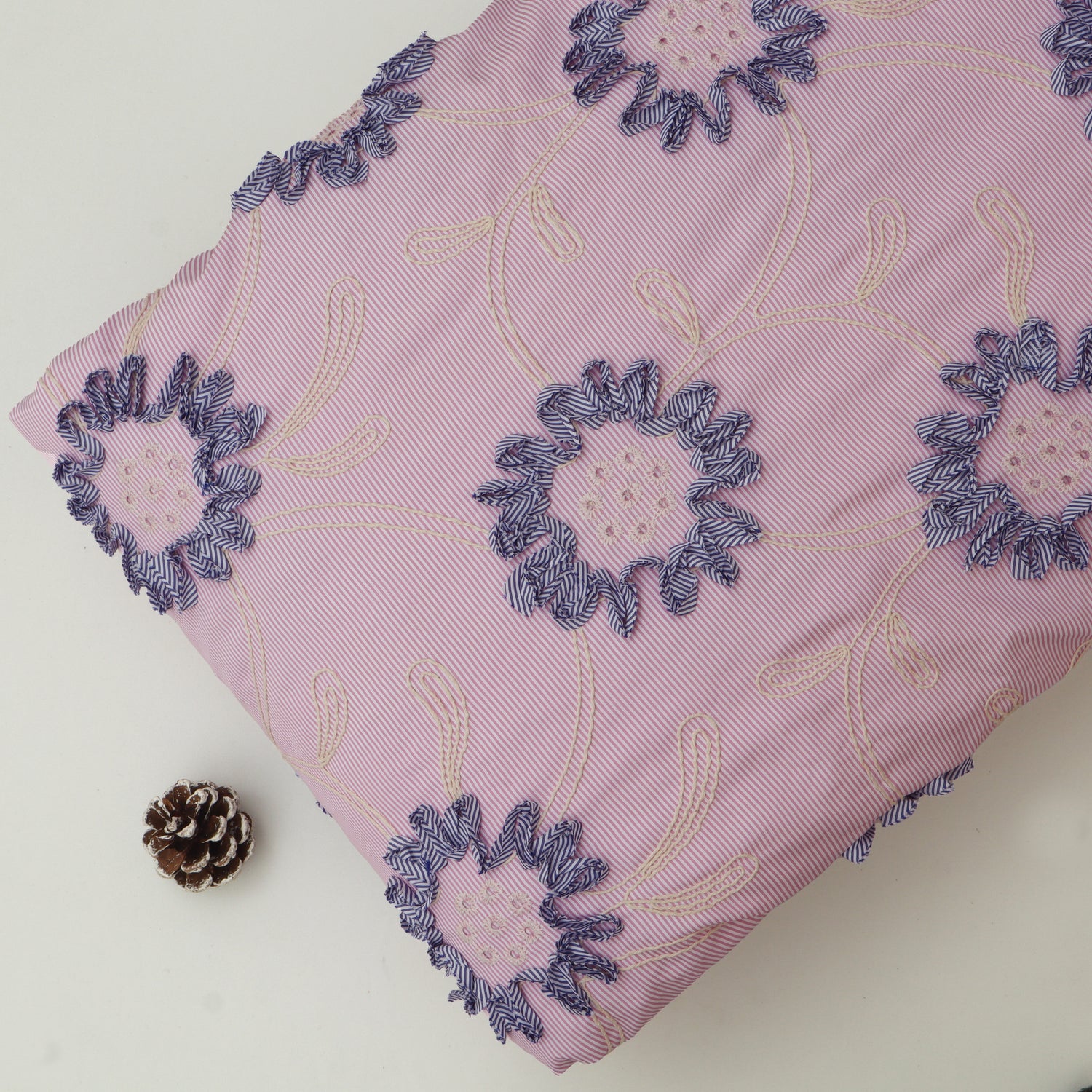 Pink fabric with embroidered blue floral patterns on a white background
