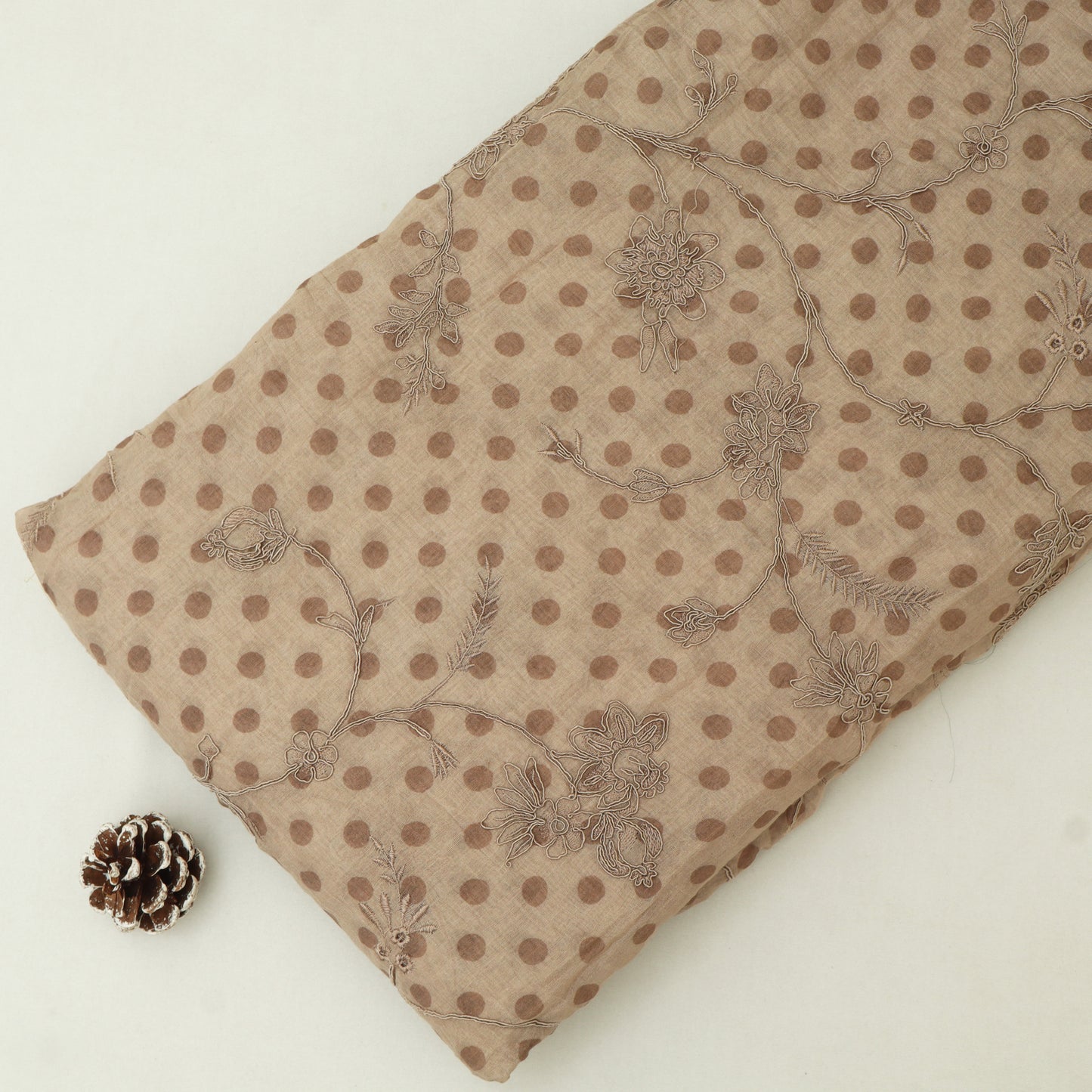Beige fabric with brown polka dots and floral patterns on a white background