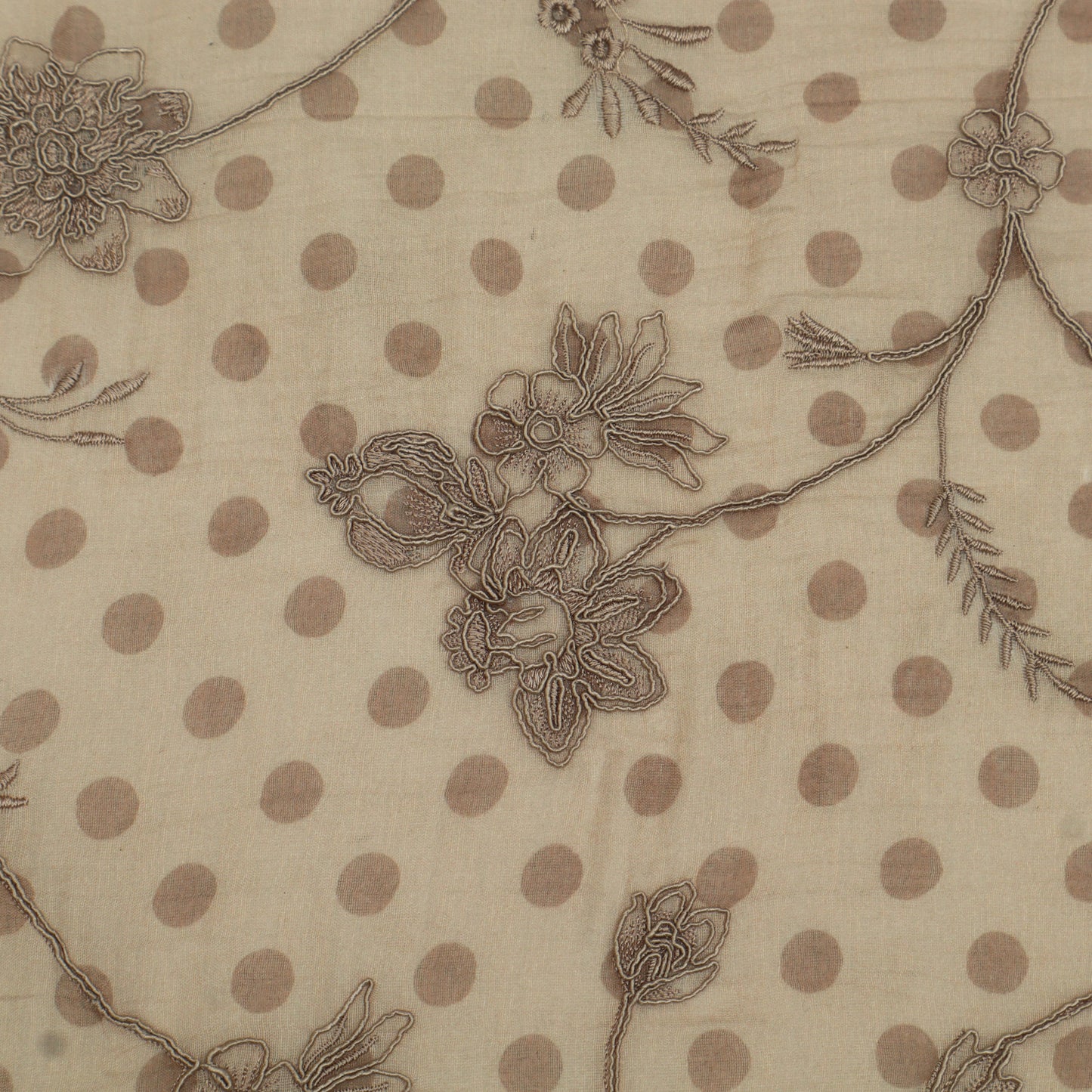 Textile with floral embroidery and polka dot pattern on beige background