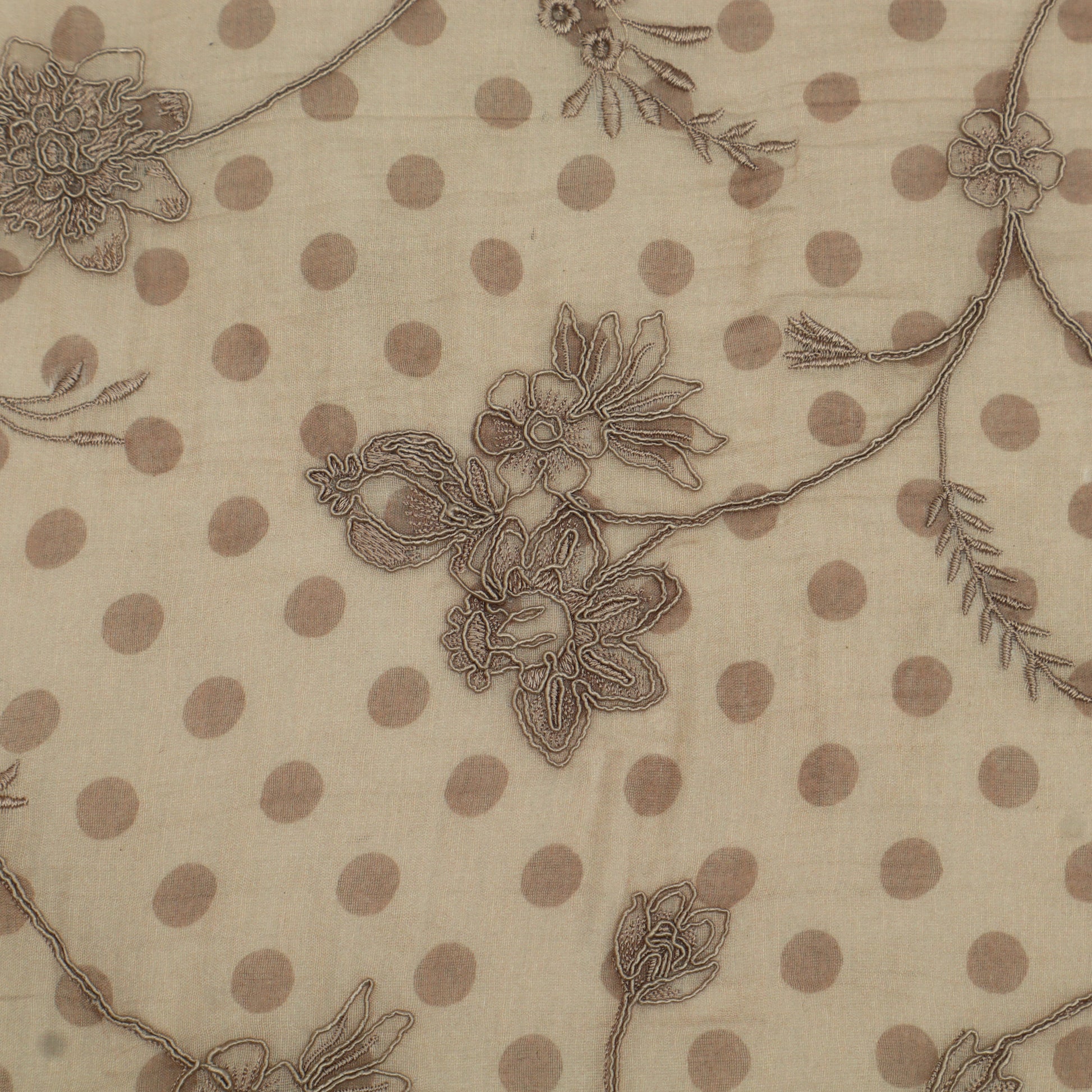 Textile with floral embroidery and polka dot pattern on beige background