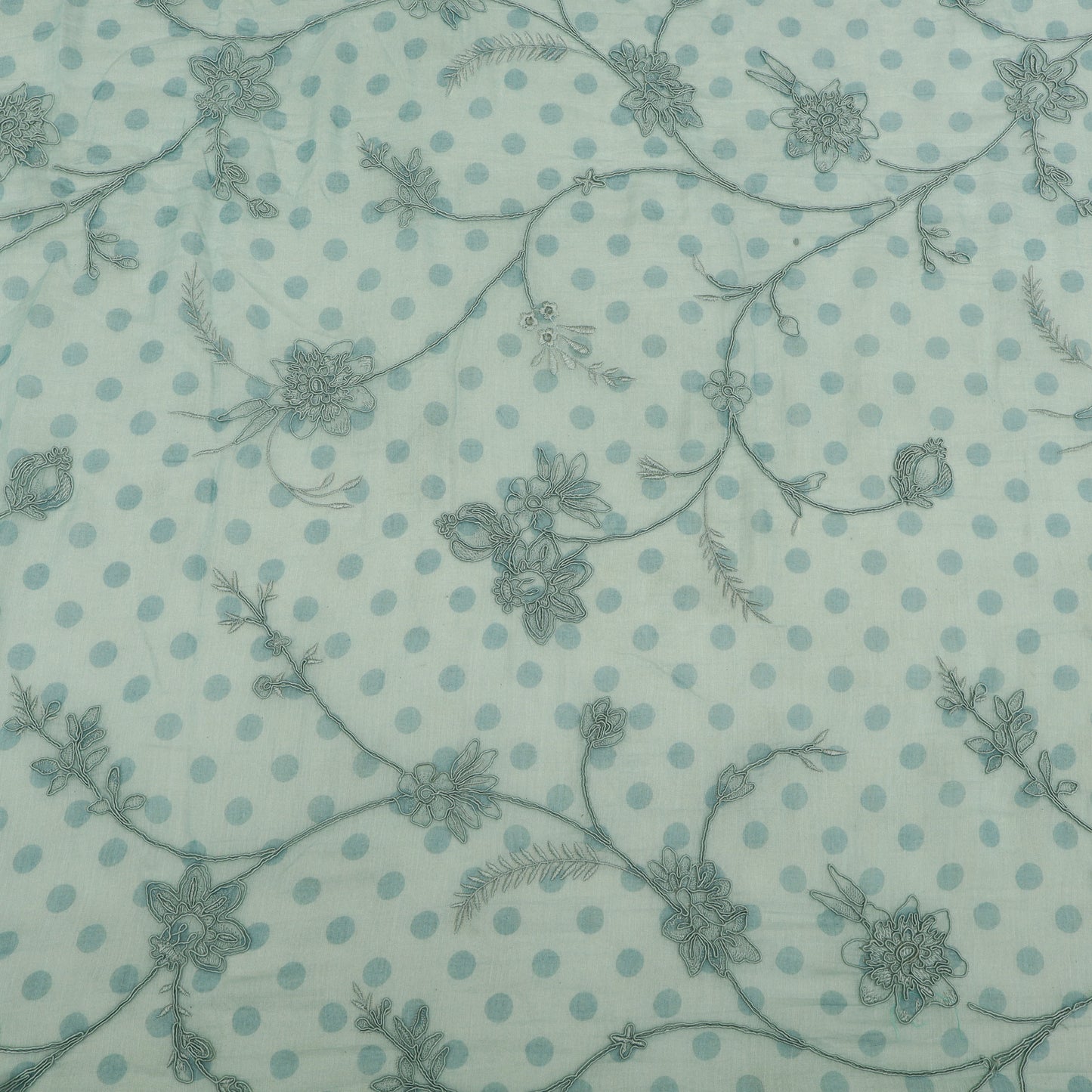 Patterned fabric with floral and polka dot design on a light blue background