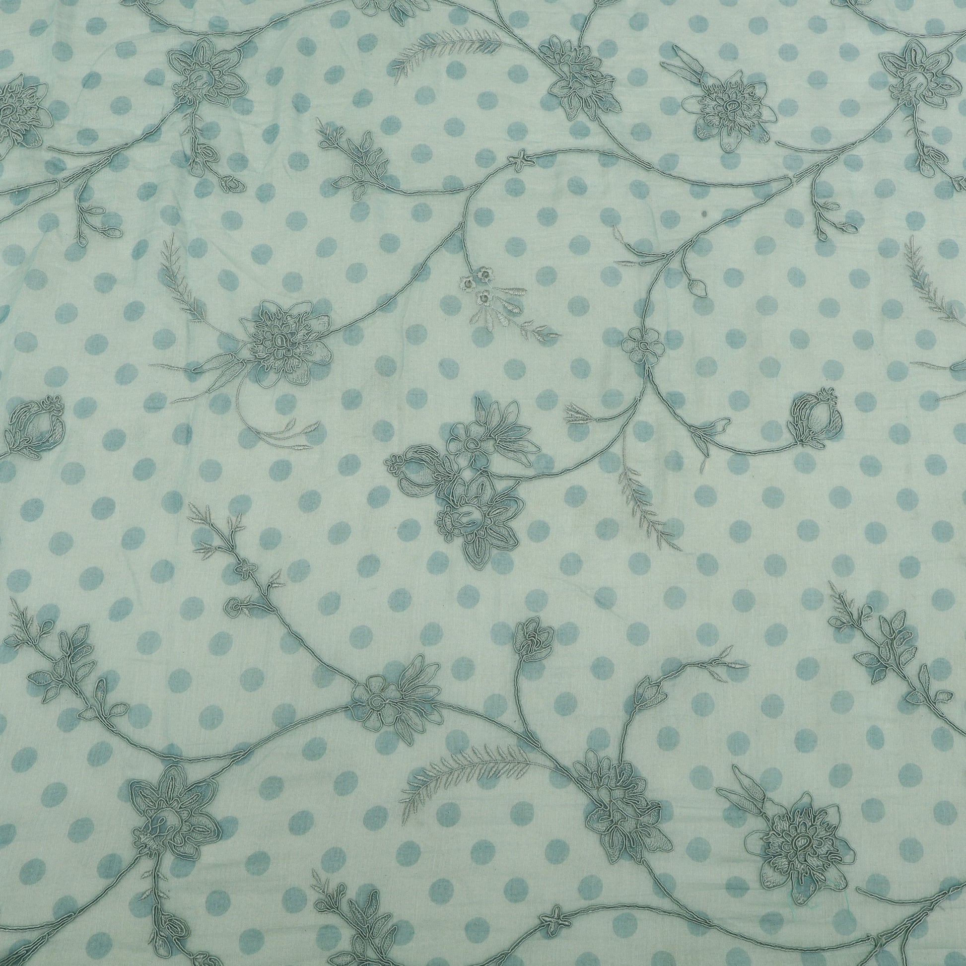 Patterned fabric with floral and polka dot design on a light blue background