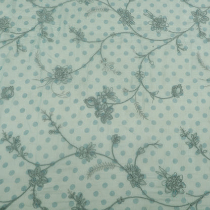 Patterned fabric with floral and polka dot design on a light blue background
