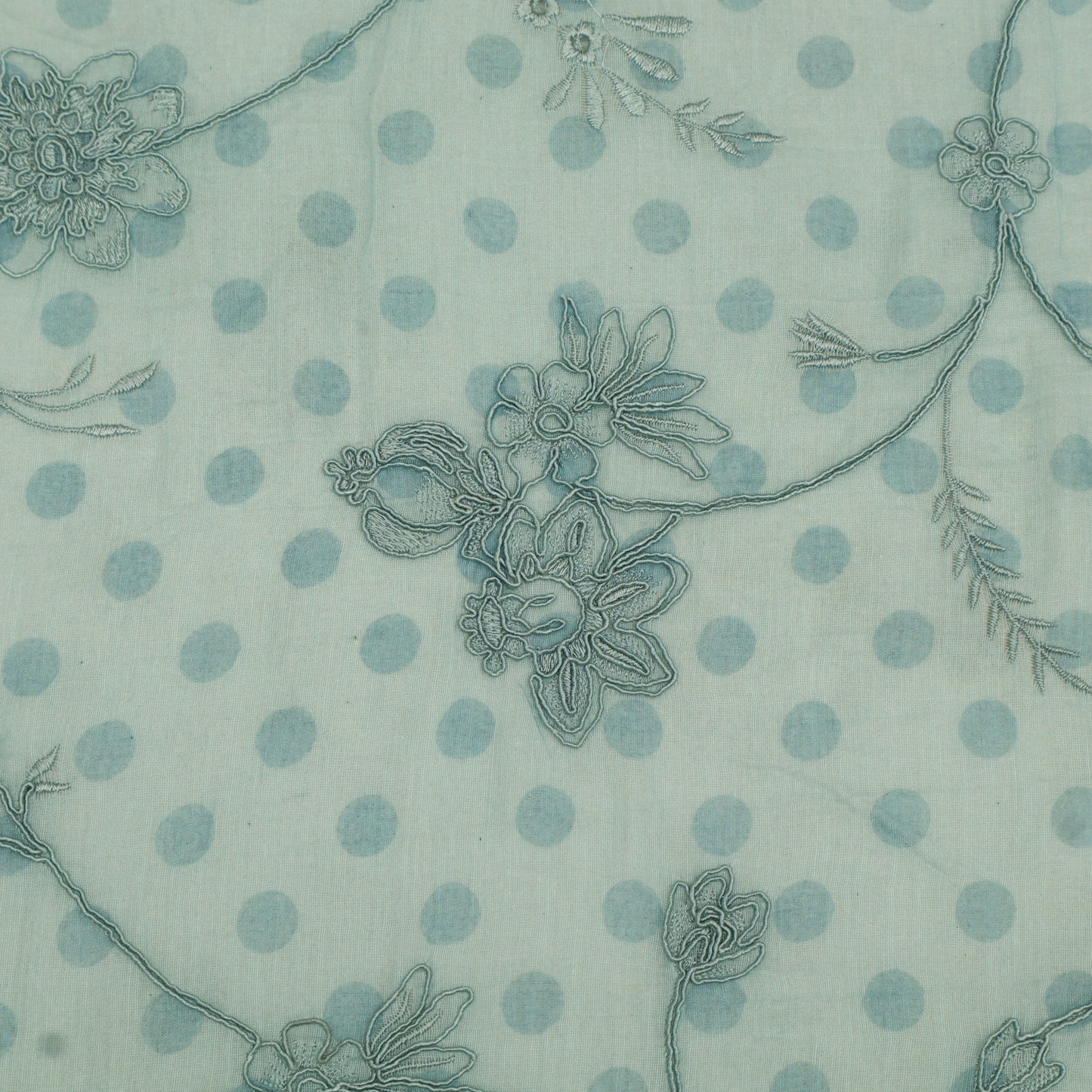 Fabric pattern with blue floral designs and polka dots on a light green background
