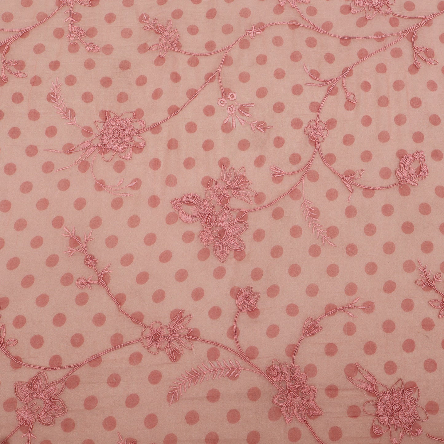 Pink polka dot fabric with floral patterns on a pink background