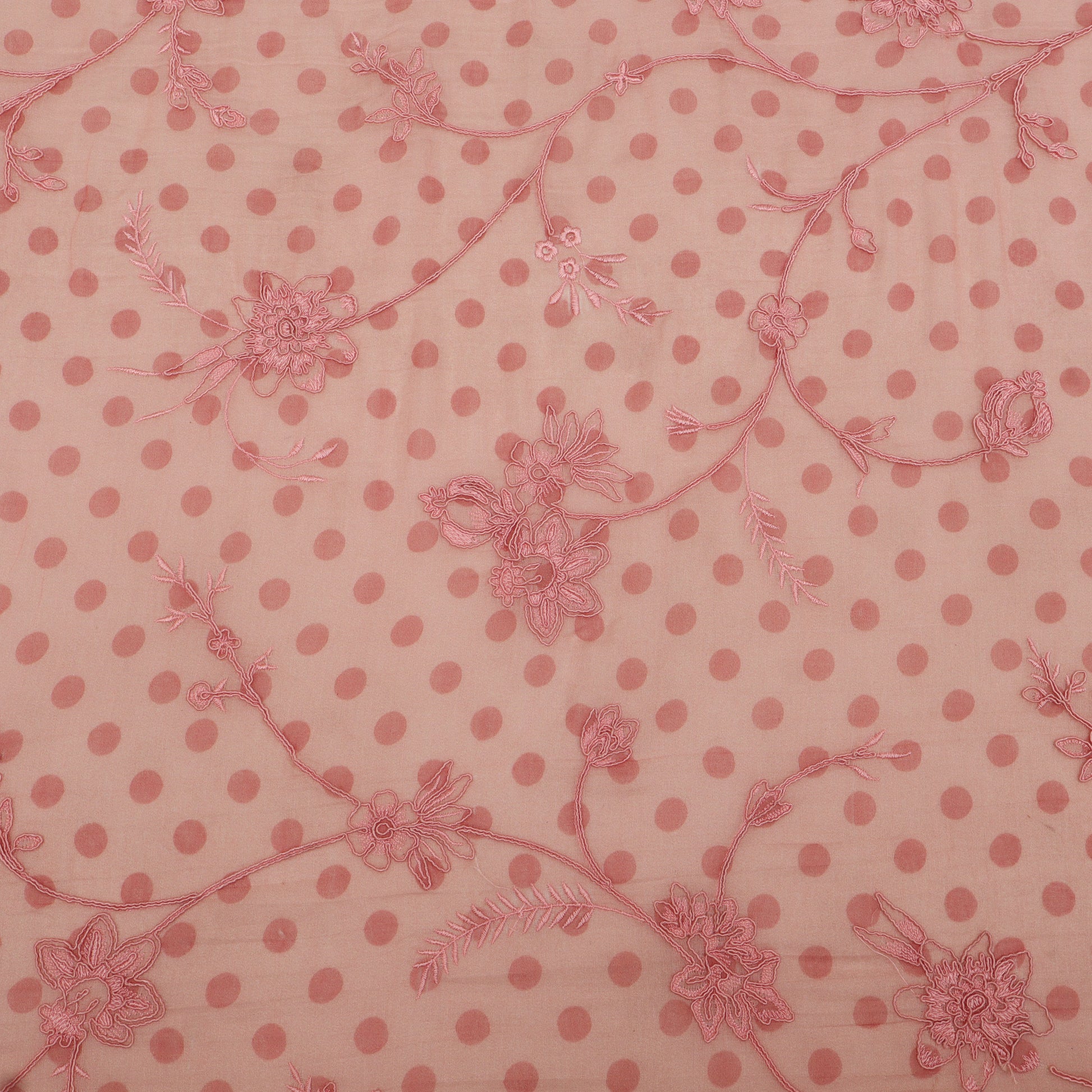 Pink polka dot fabric with floral patterns on a pink background