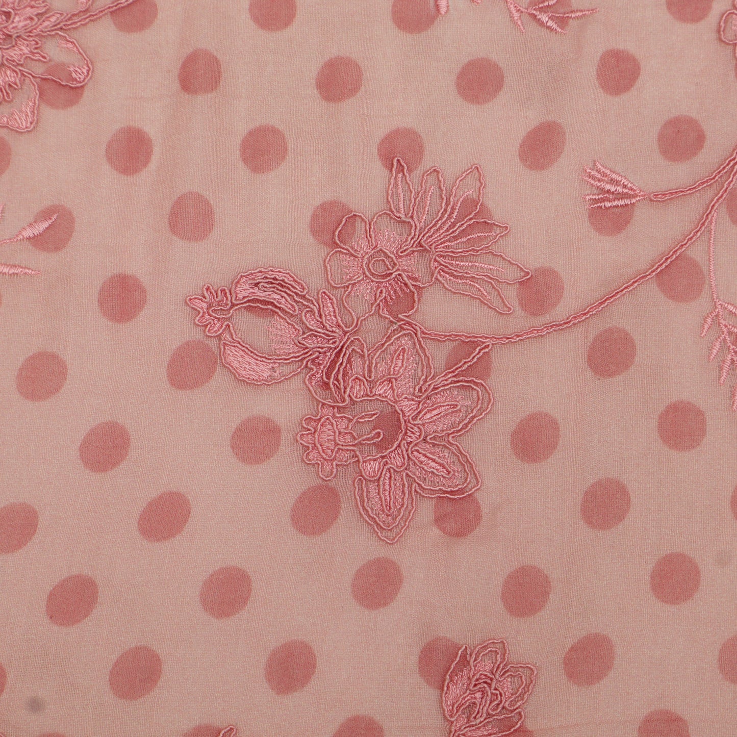 Pink polka dot fabric with floral embroidery on a pink background