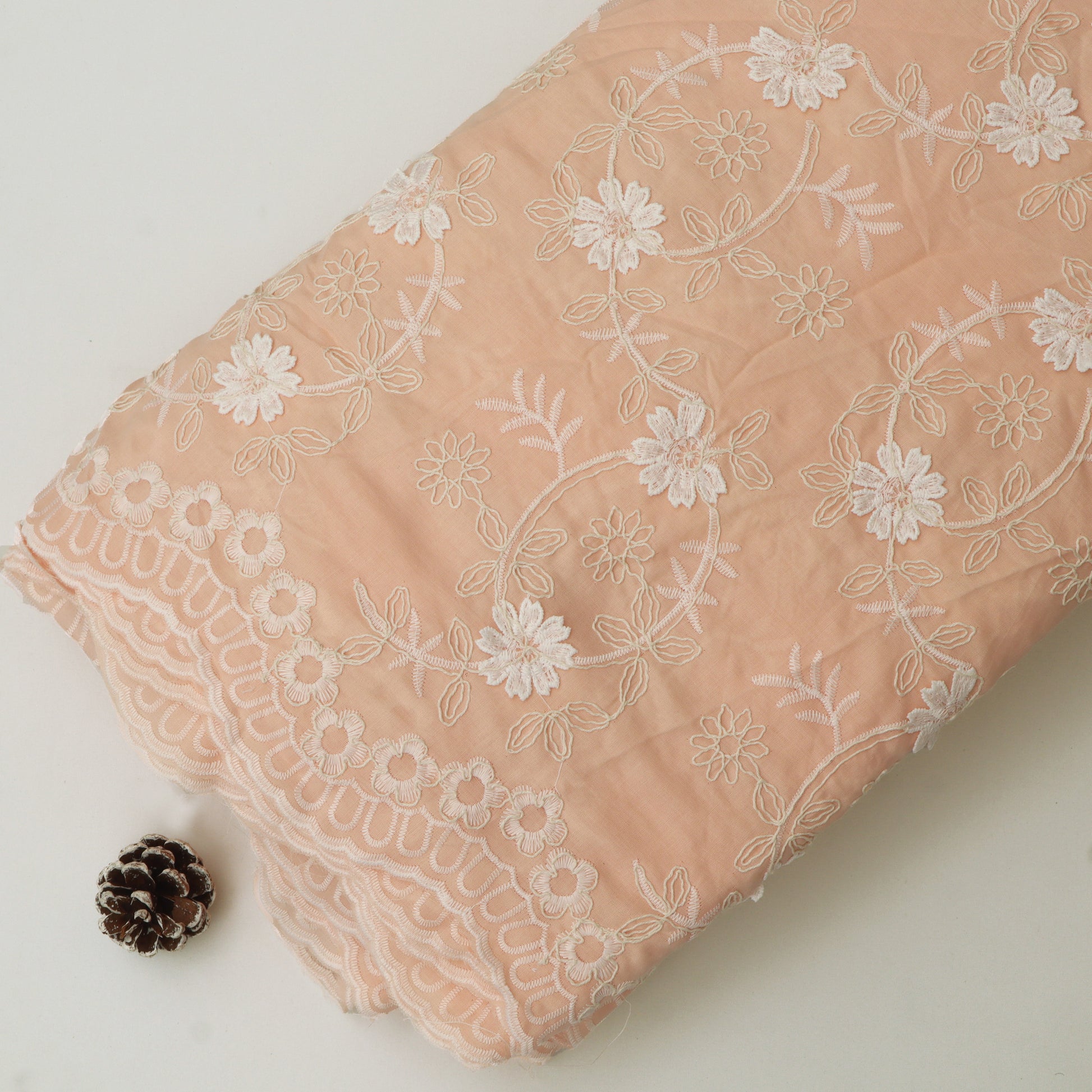 Pink fabric with white floral embroidery on a light background